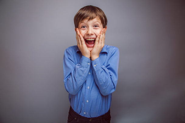 teenager boy surprised a rejoices over gray background - Φωτογραφία, εικόνα