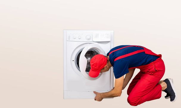 Reparador está reparando una lavadora en el fondo blanco
 - Foto, Imagen
