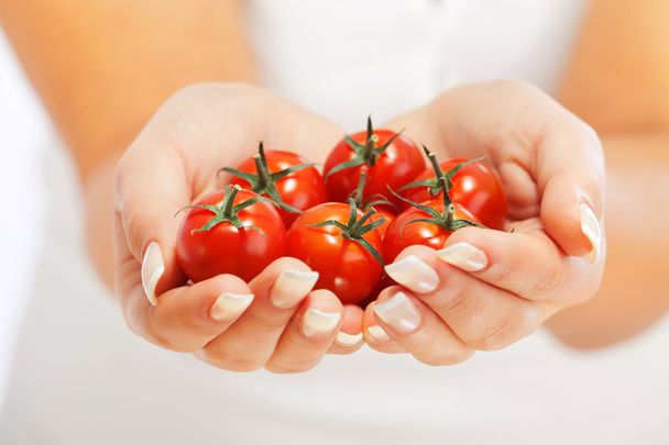 Young woman holding cherry tomatoes - Fotoğraf, Görsel
