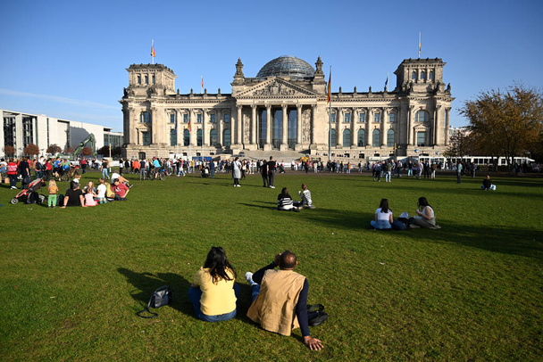 Berlin, Germany - October 31, 2022: People relax on the gras near the German Bundestag (Reichstag Building) is the national parliament of the Federal Republic of Germany. - Foto, Imagen