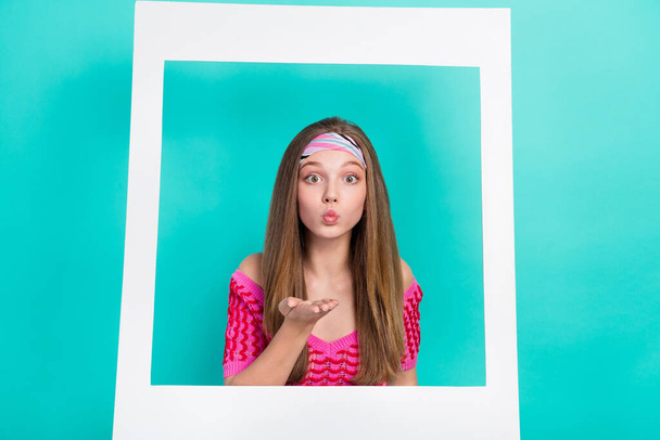 Photo of pretty adorable school girl dressed pink crop top sending kiss photographing white paper frame isolated teal color background. - Photo, Image
