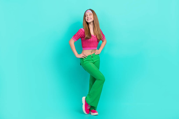 Full length photo of dreamy cute school girl dressed pink crop top flare trousers looking empty space isolated teal color background. - Fotografie, Obrázek