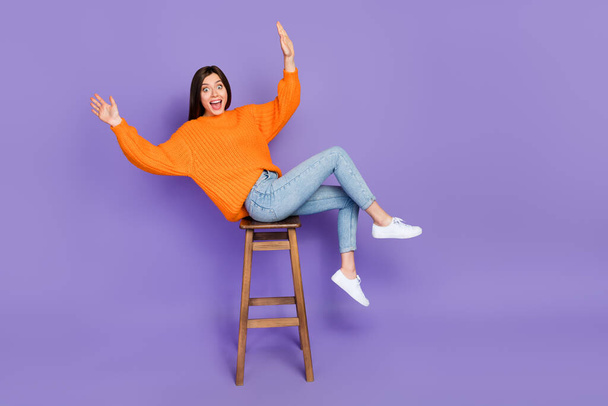 Full size photo of lovely young woman sit stool falling lean over dressed stylish orange knitted outfit isolated on purple color background. - Fotó, kép