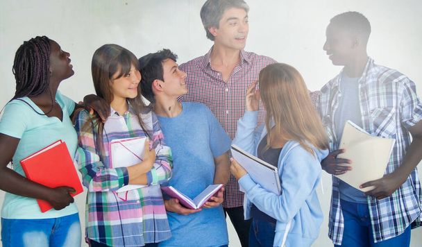 Glücklicher Teenager-Unterricht. Lehrer mit multiethnischen Klassenkameraden isoliert auf weißem Hintergrund. - Foto, Bild