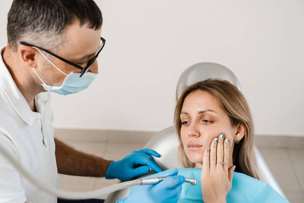 Frau mit Zahnschmerzen auf Konsultation und Behandlung beim Zahnarzt in der Stomatologie. Zahnarzt behandelt Karieszähne für Mädchen - Foto, Bild