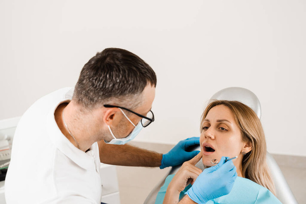 Hammaslääkäri tutkii hampaita naisen hoitoon hammassärky. Kipu hampaissa. Hammaslääkärin kuuleminen hammaslääketieteessä - Valokuva, kuva