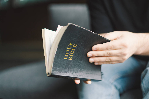 Christelijke man houdt heilige bijbel in handen. De Bijbel lezen in een tehuis. Concept voor geloof, spiritualiteit en religie. Vrede, hoop - Foto, afbeelding
