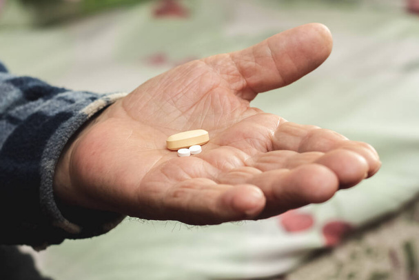 An elderly man holds pills in his hand. Taking pills to treat the disease - Photo, Image