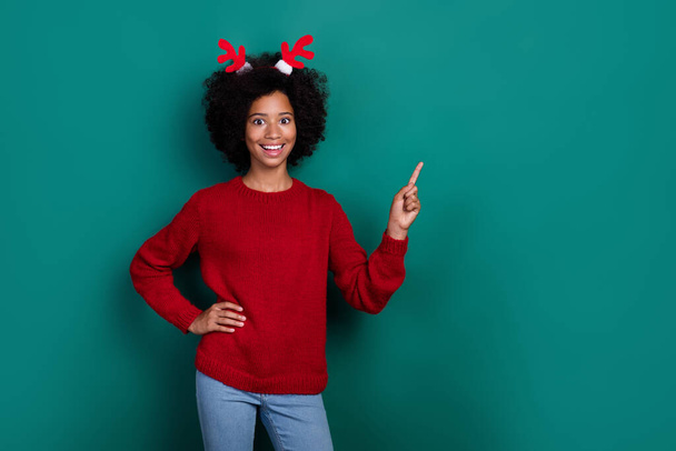 Photo of sweet charming little school girl dressed red sweater horns pointing finger empty space isolated green color background. - Photo, Image