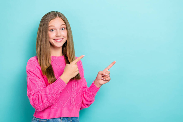 Photo of optimistic toothy beaming girl straight hairstyle wear pink knit sweater indicating empty space isolated on blue color background. - Valokuva, kuva