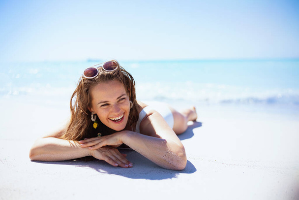 smiling modern 40 years old woman laying at the beach. - Фото, зображення