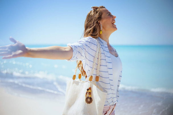 happy modern woman at the beach in white striped shirt and shorts rejoicing. - Valokuva, kuva
