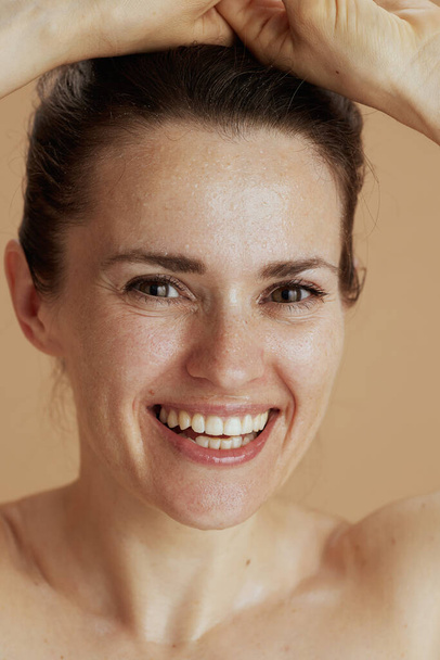happy young woman with wet face washing against beige background. - Foto, afbeelding