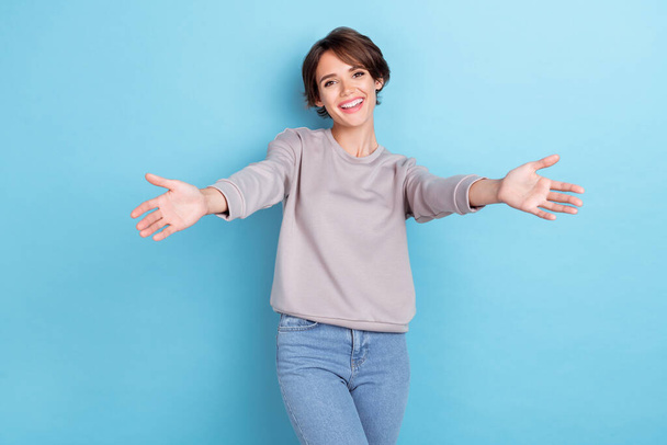 Photo of cheerful positive lady beaming smile trendy outfit sweater sweatshirt open arm want hug you isolated on blue color background. - Photo, image