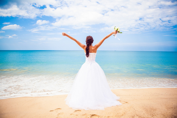 海辺の結婚式のアーチの背景にウェディング ドレスで美しい幸せな女の子 - 写真・画像