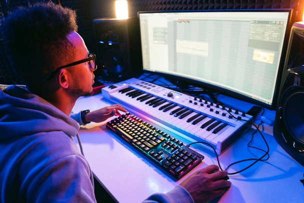 Producer, hangmérnök egy vezérlőpanelt és képernyőt használ, hogy rögzítsen egy új albumot egy stúdióban, egy hangszigetelt szobában. Képgyártó, tervező a munkafolyamatban - Fotó, kép