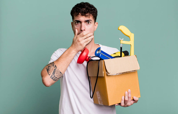 adult man covering mouth with hands with a shocked with a toolbox. housekeeper concept - Foto, imagen
