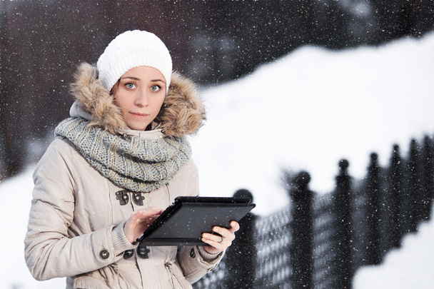 Woman on the tablet smartphone in winter park on a background of - Фото, зображення