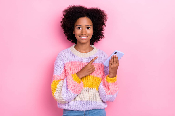 Portrait of cheerful good mood nice girl with wavy hairdo wear knit sweatshirt directing at phone isolated on pink color background. - 写真・画像
