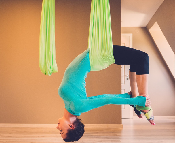 Young woman performing antigravity yoga exercise - Photo, Image