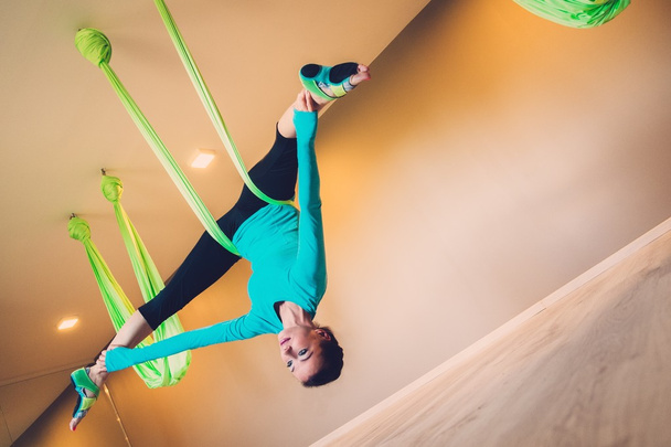 Jonge vrouw uitvoeren van anti-zwaartekracht yoga oefening - Foto, afbeelding