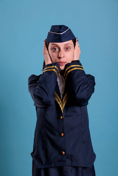 Stewardess bedeckt Ohren mit Händen und zeigt keine böse Geste. Stewardess mit Blick auf die Frontansicht der Kamera, kein Hinweisschild, drei kluge Affen - Foto, Bild