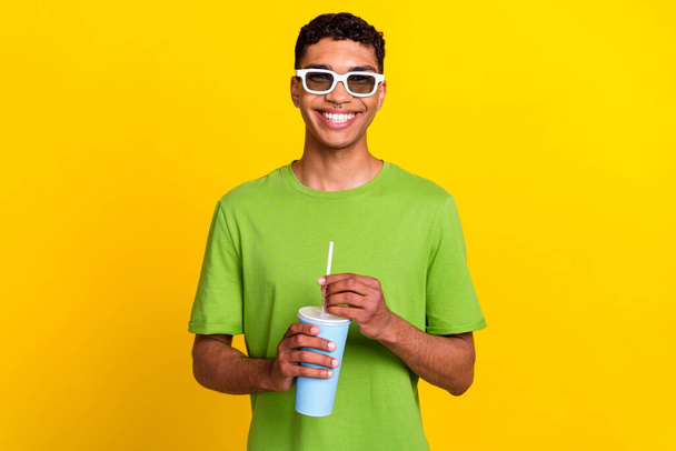 Portrét fotografie mladého pozitivního atraktivní usmívající se muž nosit bílé brýle dobrá nálada držet soda cola nápoj emoce po kině izolované na žlutém pozadí. - Fotografie, Obrázek