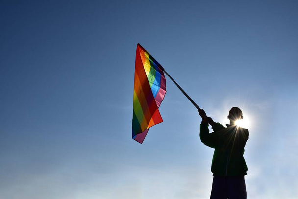 Rainbow flag holding in hand against bluesky background, concept for LGBT celebration in pride month, June, around the world. - Photo, Image