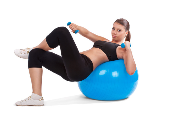 Strong girl lifting dumbbells on fitball - Фото, зображення