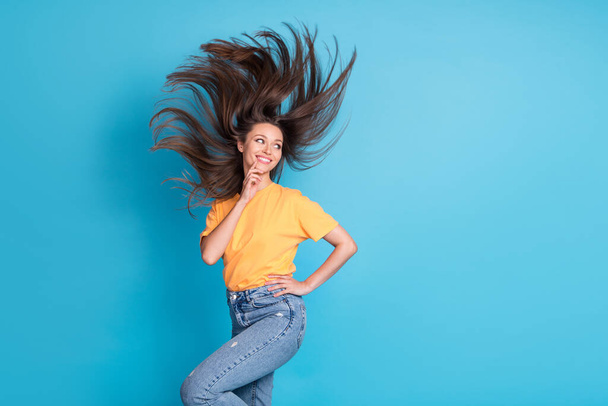 Photo of adorable dreamy lady wear yellow t-shirt hair fluttering air blowing finger chin looking empty space isolated blue color background. - Φωτογραφία, εικόνα