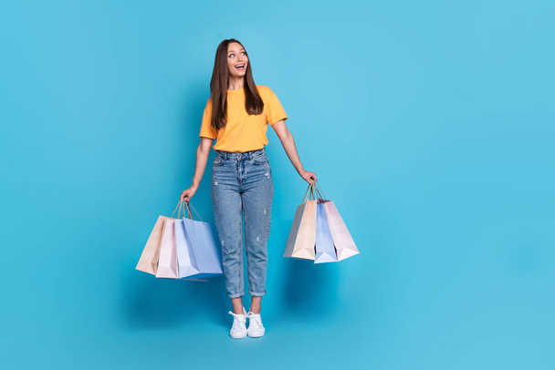 Photo of cute positive lady fashionable outfit stand toes interested look promo banner empty space isolated on blue color background. - Foto, Imagem