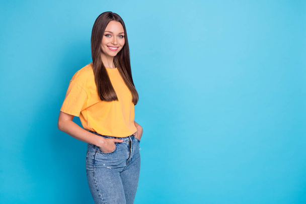 Photo of cheerful positive lady dressed yellow outfit clothes stand empty space hand arm pocket isolated on blue color background. - Zdjęcie, obraz