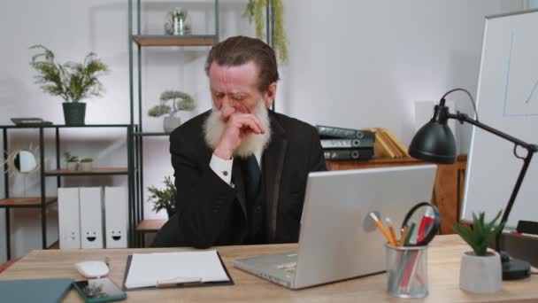 Neefektivní unavený starší podnikatel pracující na notebooku s nálepkami na obličeji na kancelářském stole. Starší lenivý manažer na volné noze. Obchodníci staří lidé podvádět spát - Záběry, video