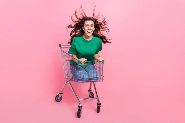 Photo of overjoyed funky lady client customer sit cart hurry store cool prices new stylish collection isolated pink color background. - Фото, зображення