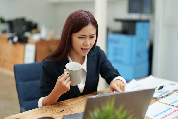 Asiatique femme d'affaires prendre une pause café tout en utilisant un ordinateur. - Photo, image