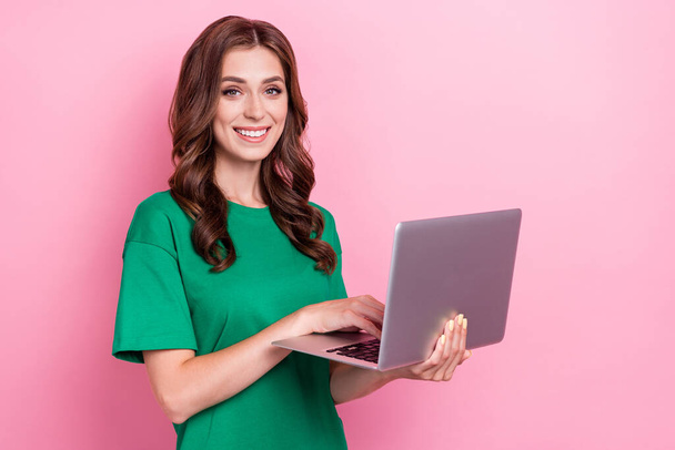 Portrait of cute nice good mood woman with wavy hairdo wear green t-shirt writing email on laptop isolated on pink color background. - Фото, изображение