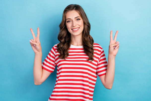 Photo of charming pretty nice curly brown hair woman wear red striped t-shirt showing v-sign hello symbol friendly isolated on blue color background. - Photo, image