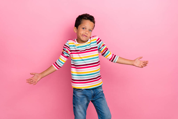Portrait of nice cute schoolboy wavy hairdo wear striped long sleeve shrugging shoulder excusing isolated on pink color background. - 写真・画像