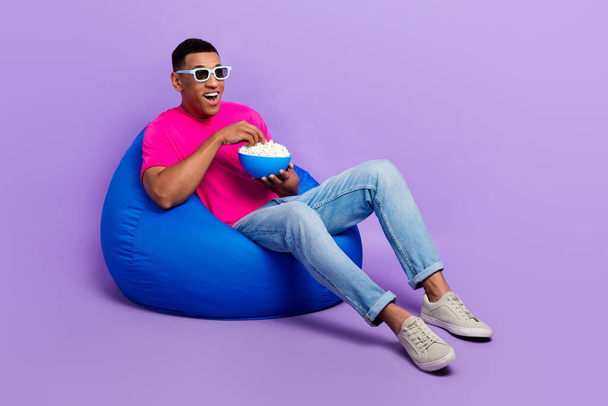 Full body photo of crazy astonished person sit cozy bag hold popcorn plate isolated on violet color background. - Valokuva, kuva