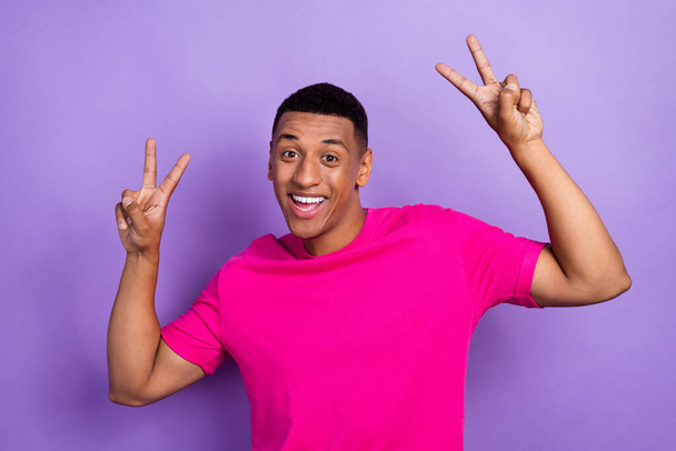 Portrait of cheerful toothy beaming man with fade haircut wear pink t-shirt showing v-sign symbol isolated on violet color background. - Foto, immagini