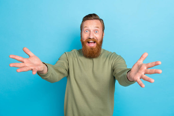 Photo of impressed overjoyed guy with ginger hairdo dressed khaki long sleeve open mouth glad to see you isolated on blue color background. - Foto, afbeelding