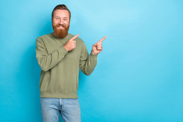 Photo of cheerful optimistic man with red hairstyle wear khaki long sleeve directing empty space isolated on teal color background. - Fotografie, Obrázek