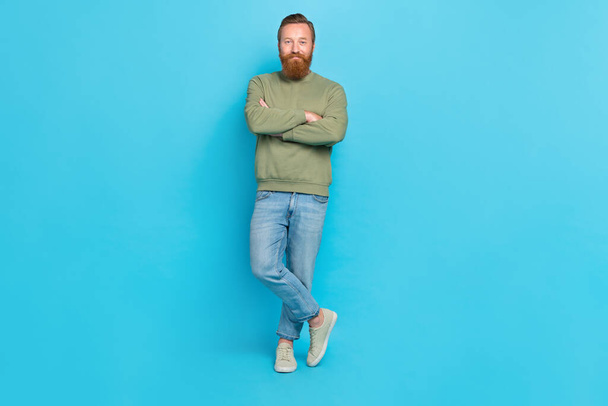 Full size photo of glad confident man with red hairstyle dressed khaki pullover standing hands crossed isolated on blue color background. - Φωτογραφία, εικόνα