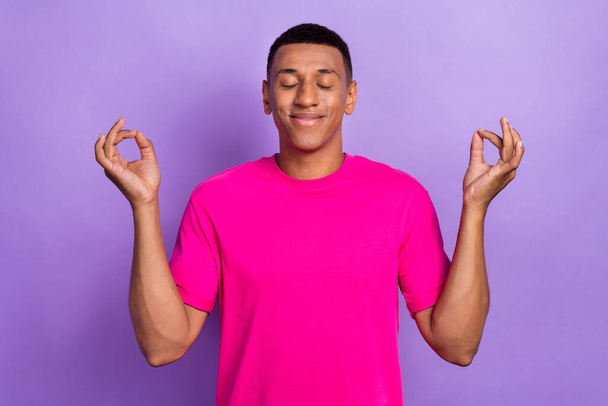 Photo of relaxed good mood positive guy box haircut dressed pink t-shirt meditating concentrating isolated on purple color background. - Foto, immagini