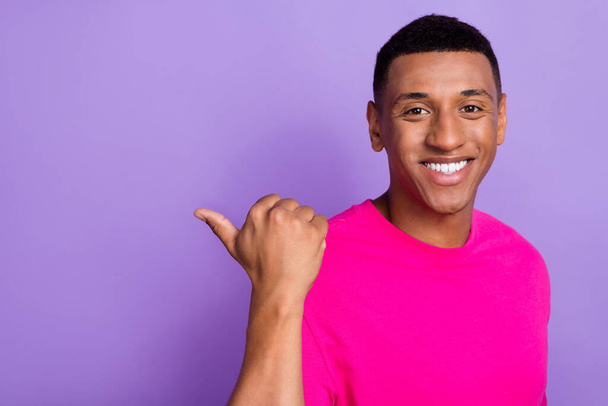 Photo of good mood optimistic satisfied guy box haircut dressed pink t-shirt directing empty space isolated on purple color background. - Фото, зображення