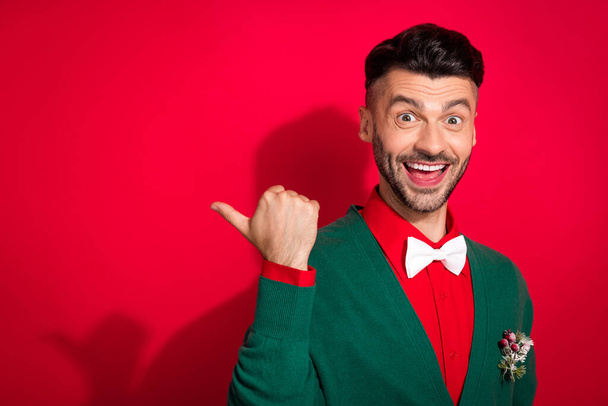 Closeup portrait photo of brunet santa claus guy wear stylish green cardigan thumb directing winter sale empty space isolated on red color background. - Φωτογραφία, εικόνα
