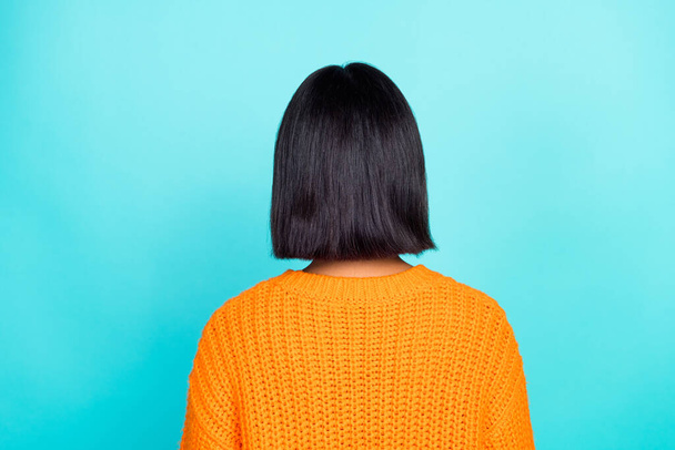 Fénykép a gyönyörű szép lány öltözött narancs pulóver álló vissza fekete selymes haj elszigetelt varangy szín háttér. - Fotó, kép