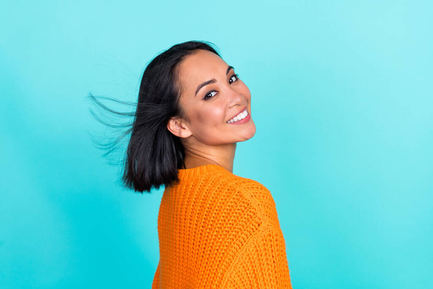 Photo of funky adorable girl dressed orange pullover smiling air blowing isolated teal color background. - 写真・画像