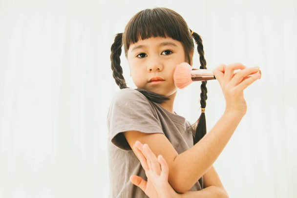 Retrato joven asiático chica maquillaje artista con cepillos en hermosas mejillas, impecablemente magnífico maquillaje en polvo, encantadora mirada a la cámara. - Foto, Imagen