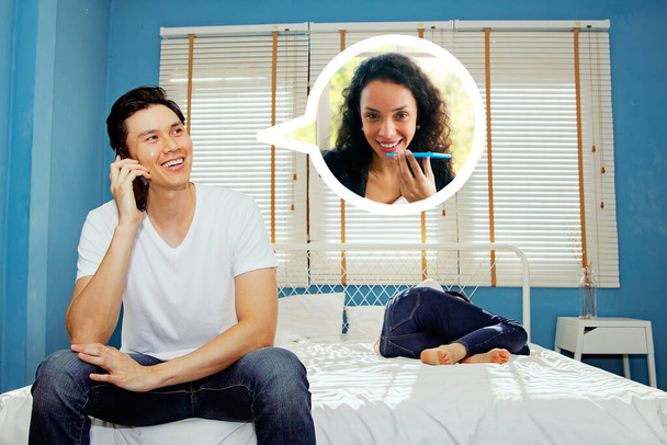 Bonito asiático flerte secretamente conversando com alguém em seu smartphone em segredo com bela mulher espanhola tendo bate-papo amigável enquanto sua namorada dorme na cama: Conceito de problemas familiares - Foto, Imagem
